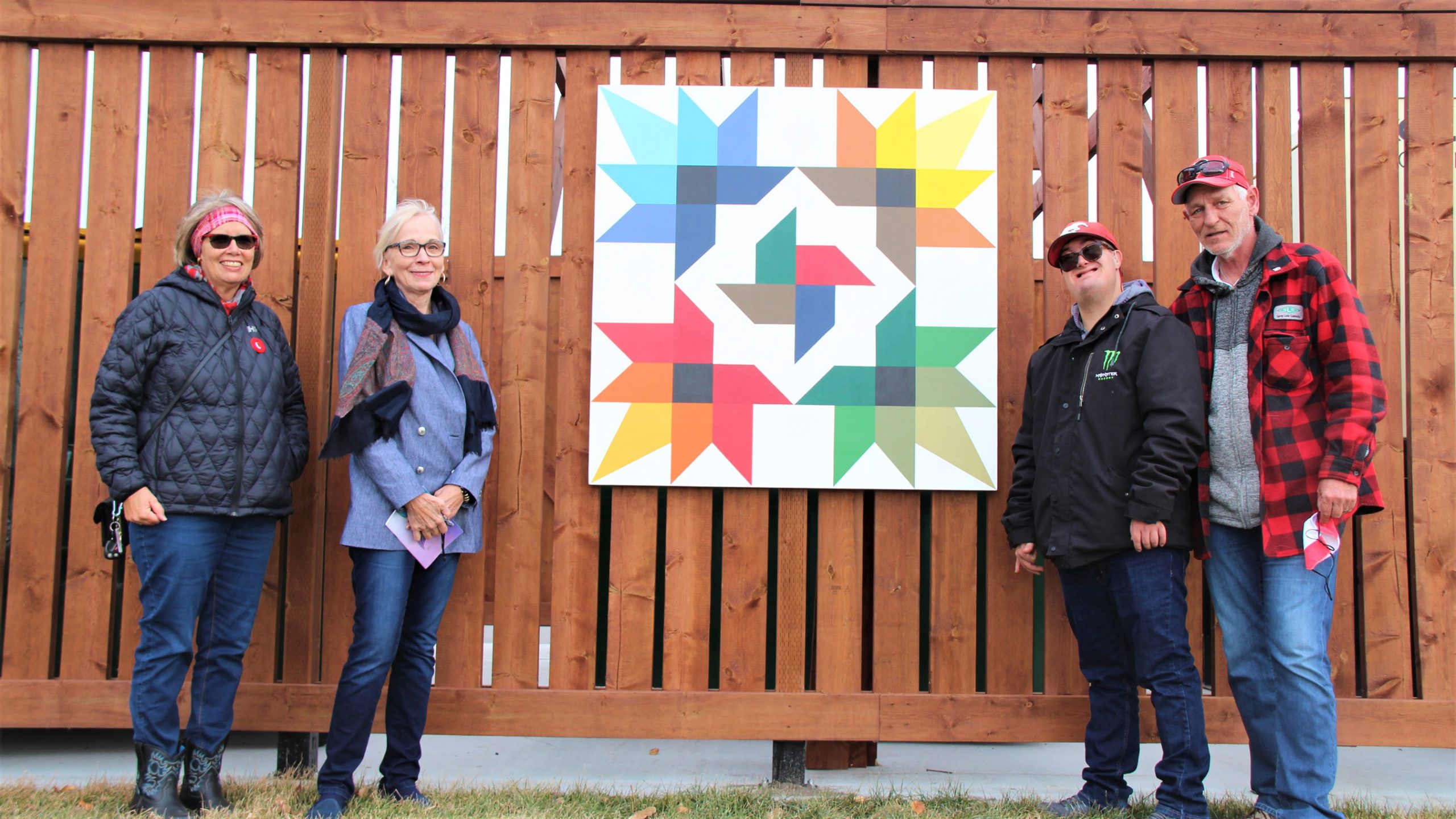 Members of the Hope Bridges Society stand beside the newest painted quilt at the Strathmore Municipal Building.