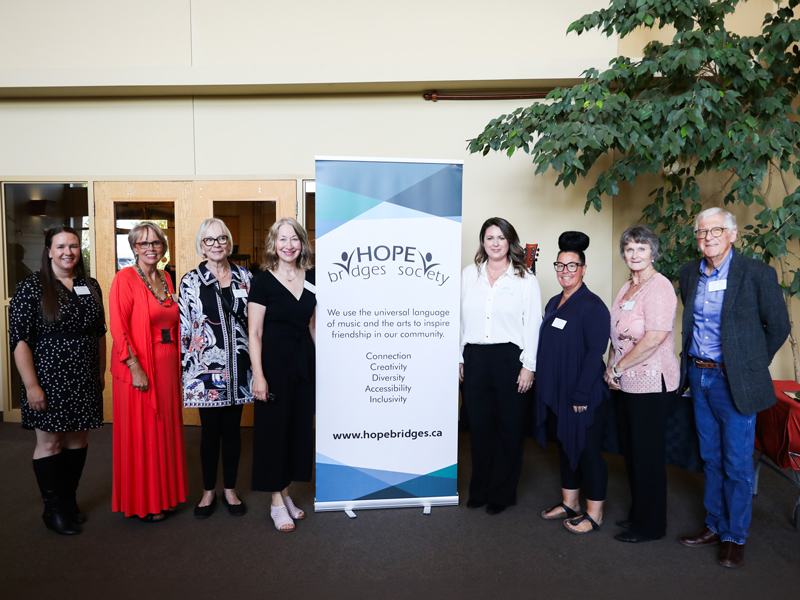 Hope Bridges Society Board Of Directors posing with (hopebridges.ca) banner highlighting its mission to use music and the arts to inspire friendship, with values listed: Connection, Creativity, Diversity, Accessibility, and Inclusivity.